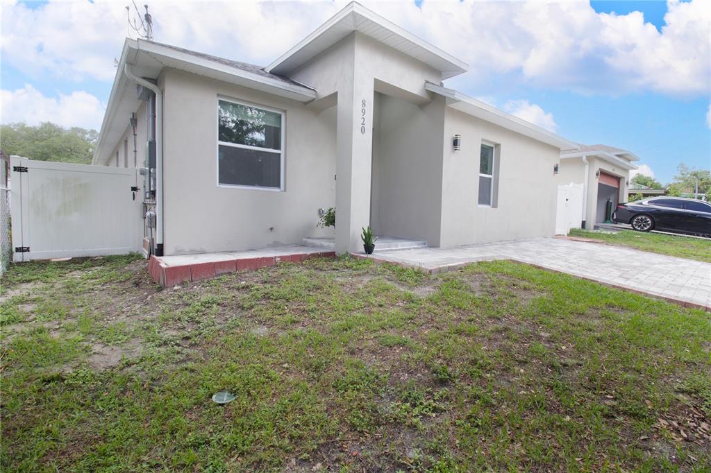 A single-story house with a light-colored stucco exterior, a paved driveway, and a front entrance — 8920 N NEWPORT AVENUE, TAMPA, FL