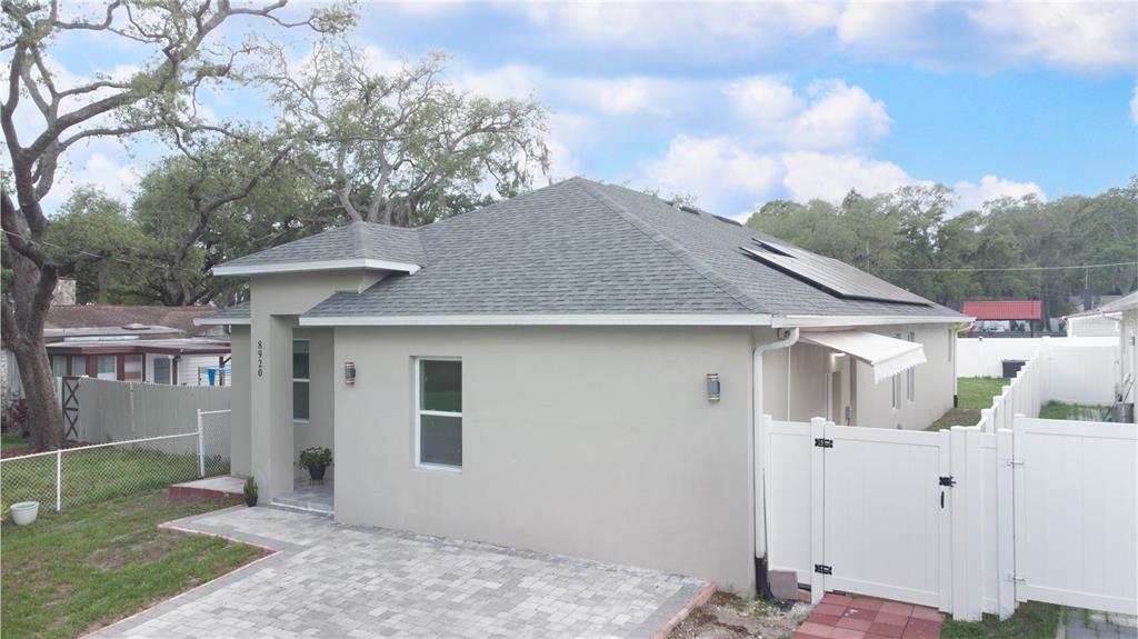 A single-story house with a gray shingled roof, solar panels, and a paved driveway — 8920 N NEWPORT AVENUE, TAMPA, FL
