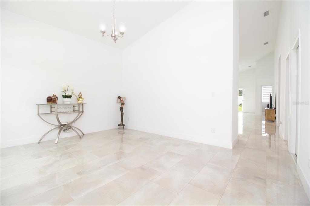 A bright, empty room with white walls, tile flooring, and a glass-topped console table — 8920 N NEWPORT AVENUE, TAMPA, FL