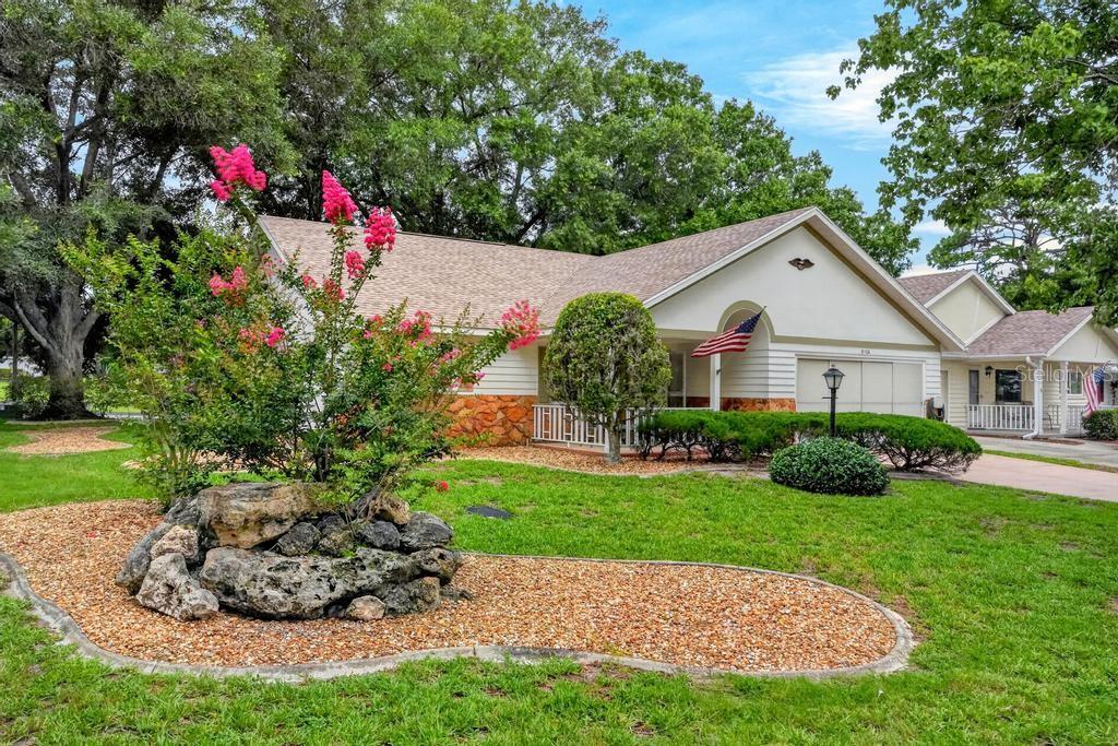 A single-story house with a stone-accented exterior, a landscaped rock garden, and a blooming tree — 9110 SW 89TH TERRACE UNIT A, OCALA, FL