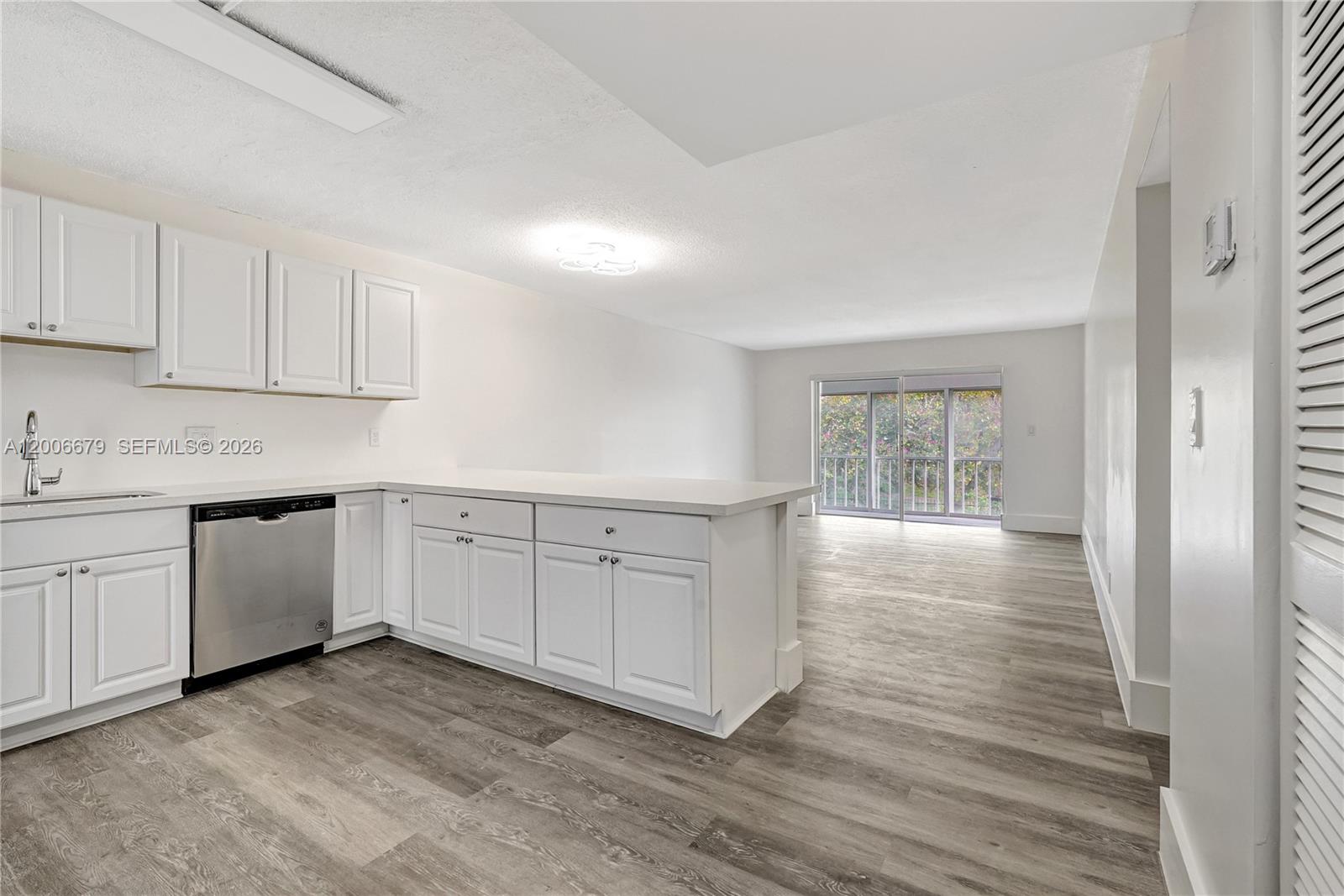 A kitchen with white cabinets and stainless steel appliances opens into a living area — 4800 Hillcrest Ln # 207, Hollywood FL 33021, HOLLYWOOD, FL