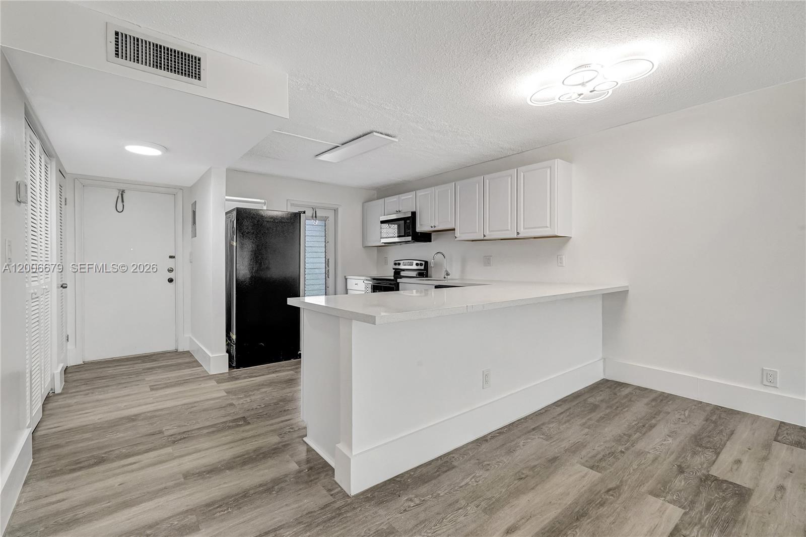 A kitchen features white cabinets, a black refrigerator, and a white peninsula countertop — 4800 Hillcrest Ln # 207, Hollywood FL 33021, HOLLYWOOD, FL