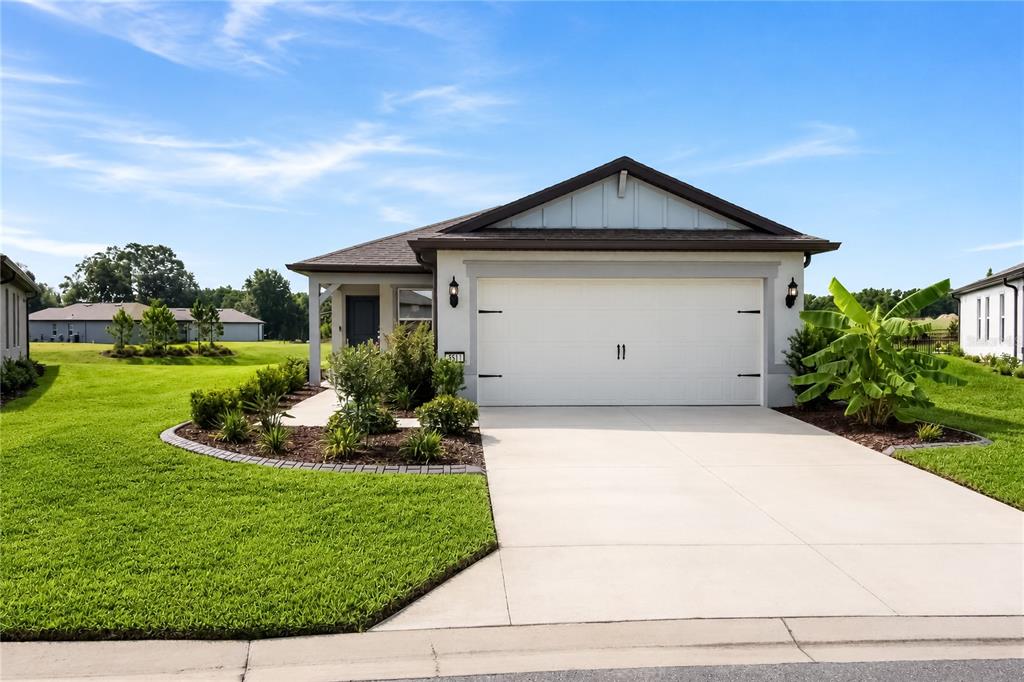 A single-story house with a white garage, gray trim, and a landscaped front yard — 5517 SW 85TH AVENUE ROAD, OCALA, FL