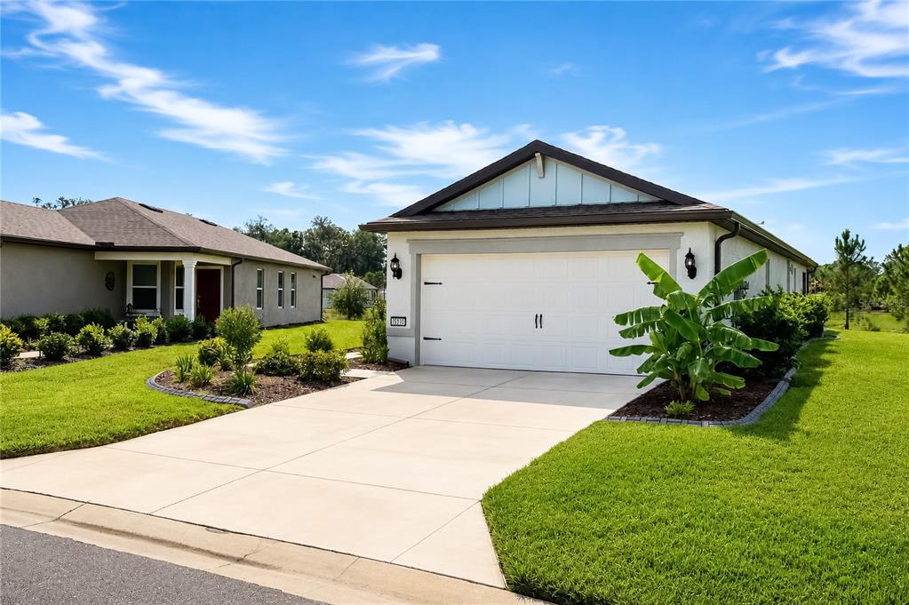 A single-story house with a white garage door, light-colored siding, and a landscaped front yard — 5517 SW 85TH AVENUE ROAD, OCALA, FL