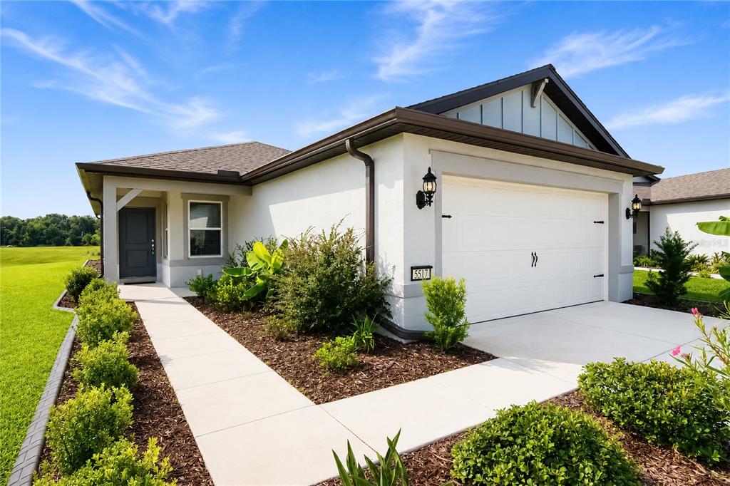 A single-story house with a white stucco exterior, a two-car garage, and a concrete walkway — 5517 SW 85TH AVENUE ROAD, OCALA, FL