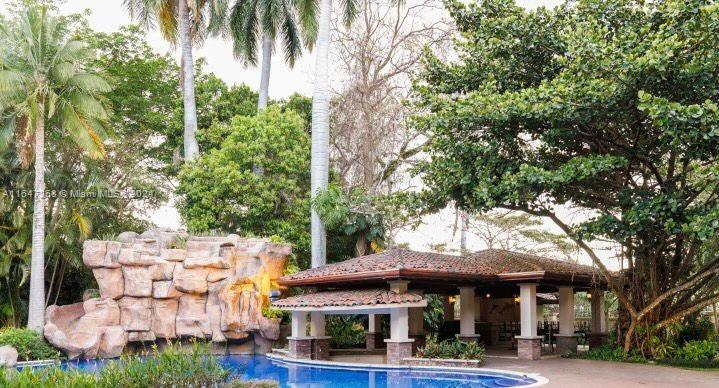 A swimming pool with a rock waterfall feature sits beside a covered outdoor patio area — San Rafael Escazu San Jose Prov. Escazu, CR, CR