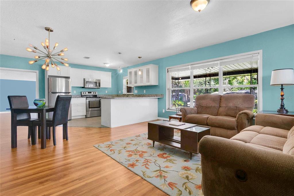 An open-concept living and dining area features light blue walls, hardwood floors, and white cabinetry — 2418 E JERSEY AVENUE, ORLANDO, FL