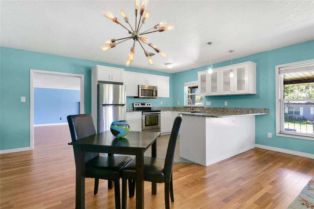 A kitchen with teal walls, white cabinets, granite countertops, and a modern sputnik chandelier — 2418 E JERSEY AVENUE, ORLANDO, FL