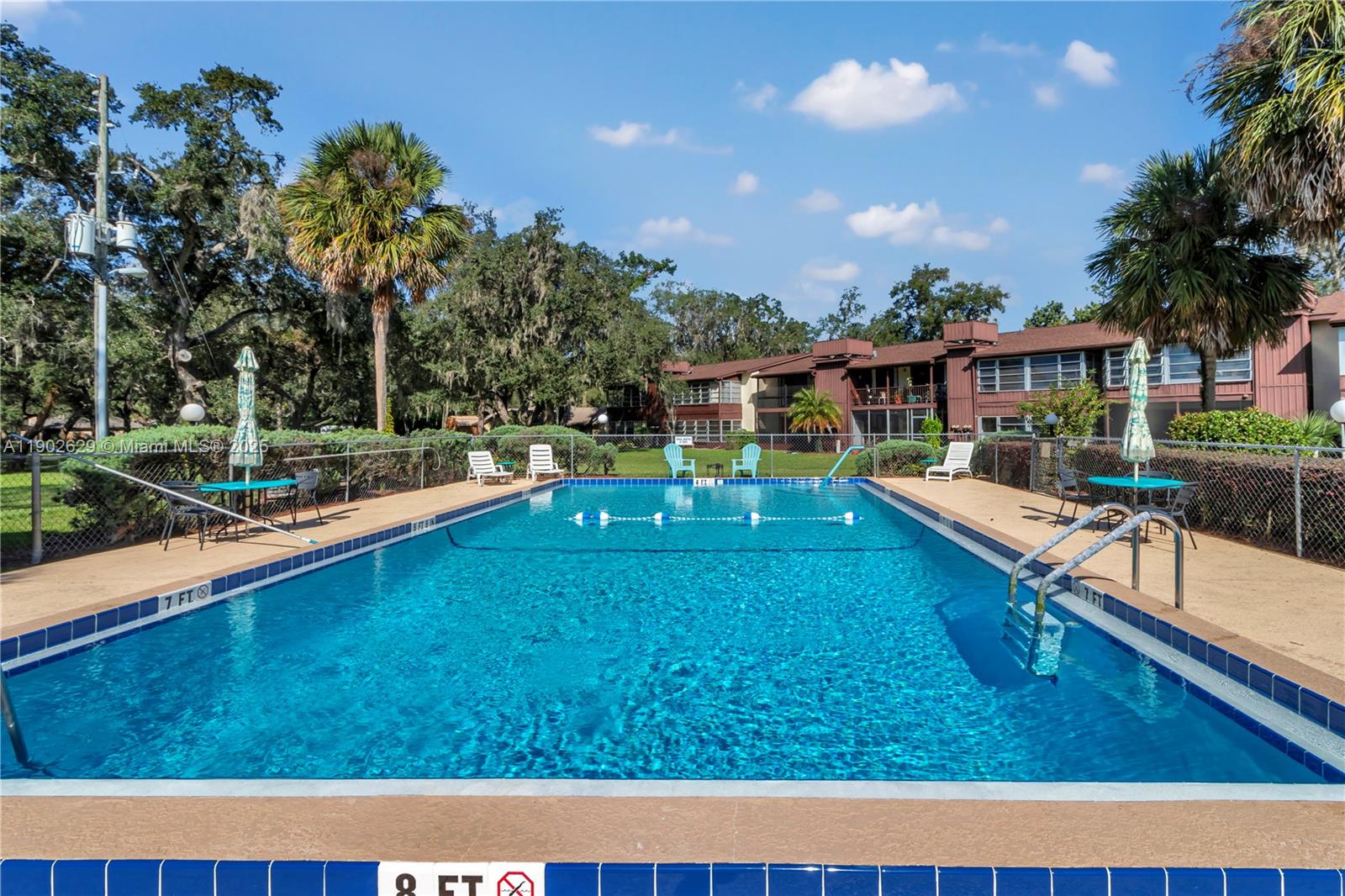 An outdoor rectangular swimming pool is surrounded by a concrete deck, lounge chairs, and trees — 737 Midway Dr # B, Ocala FL 34472, OCALA, FL