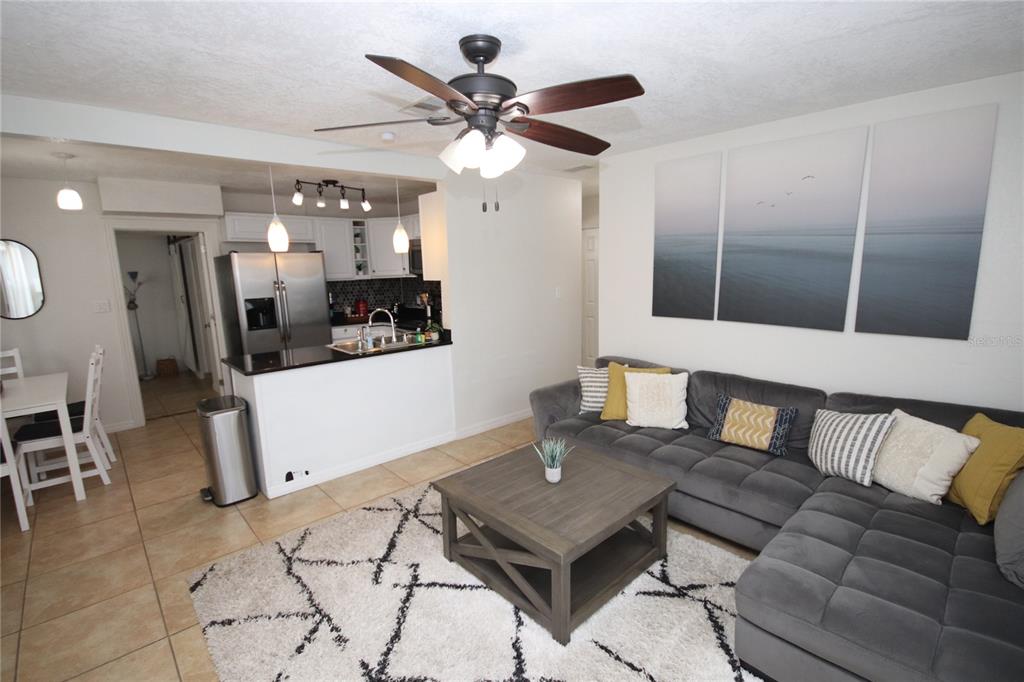 A living room with a gray sectional sofa, coffee table, and an open kitchen area — 1918 W WALNUT STREET, TAMPA, FL