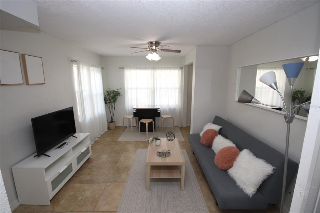 A living room with tile floors, a gray sofa, a TV stand, and a dining area — 1918 W WALNUT STREET, TAMPA, FL