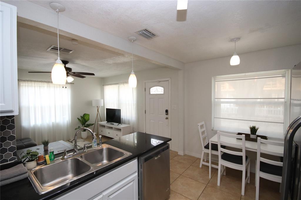 A kitchen with black countertops and stainless steel sink overlooks a dining area and living room — 1918 W WALNUT STREET, TAMPA, FL