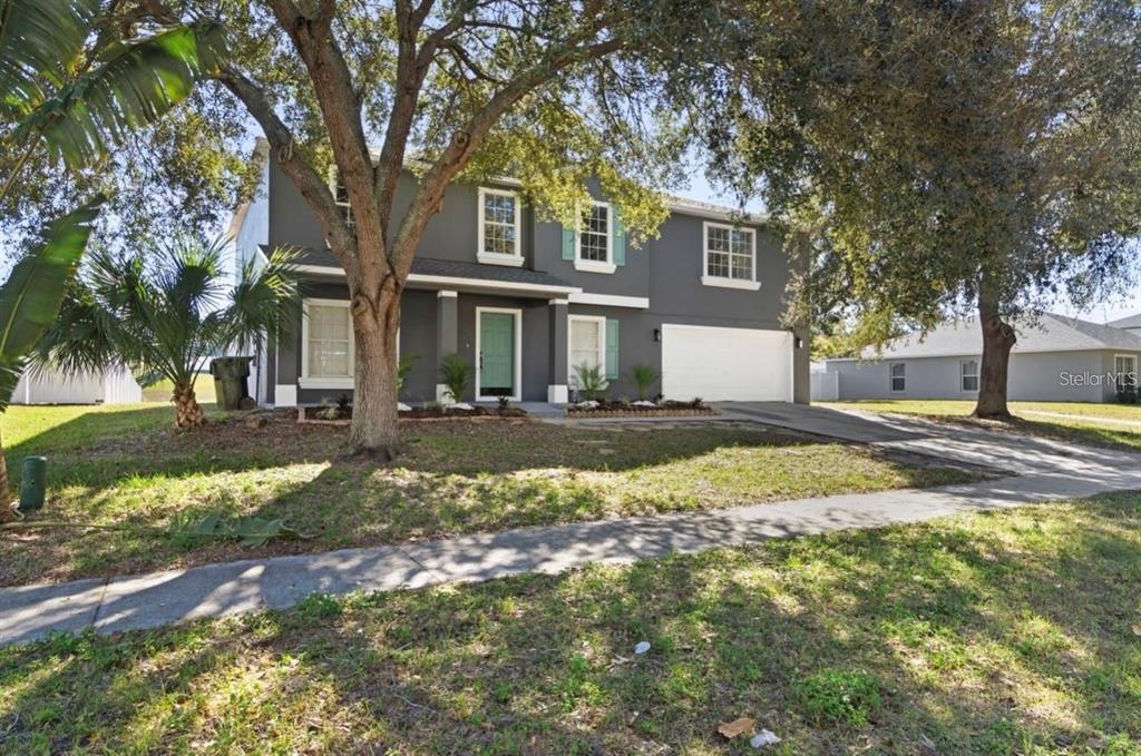 A two-story house with dark gray siding, a white garage door, and a front lawn — 1893 VALE DRIVE, CLERMONT, FL