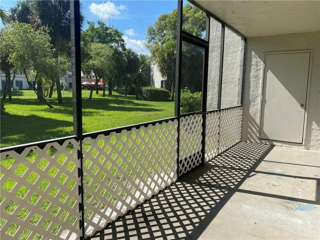 A screened-in patio features white lattice railings, a concrete floor, and a view of trees — 1230 S Military Trail # 2011, Deerfield Beach FL 33442, DEERFIELD BEACH, FL