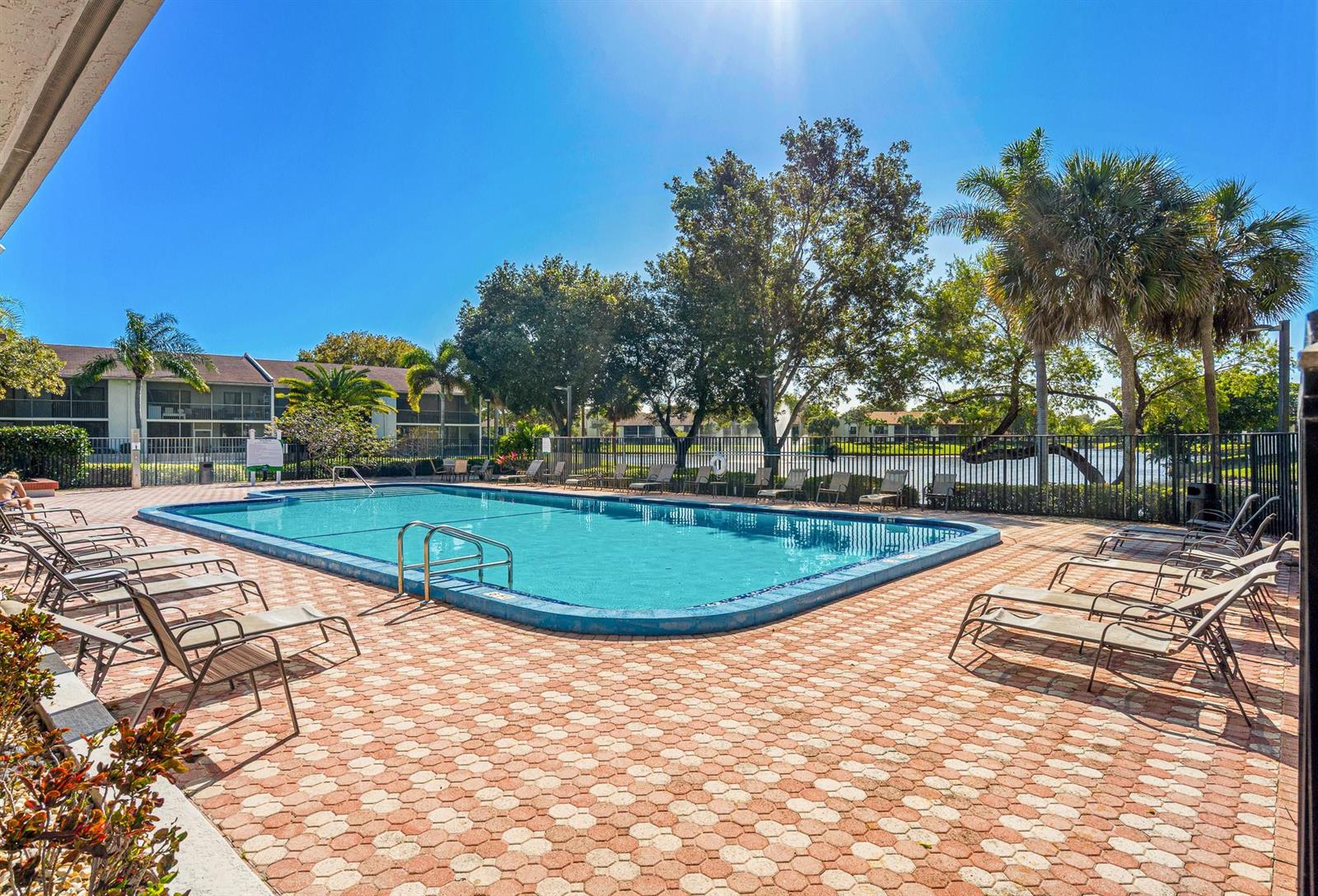 An outdoor swimming pool surrounded by lounge chairs and a brick patio near a lake — 1230 S Military Trail # 2011, Deerfield Beach FL 33442, DEERFIELD BEACH, FL