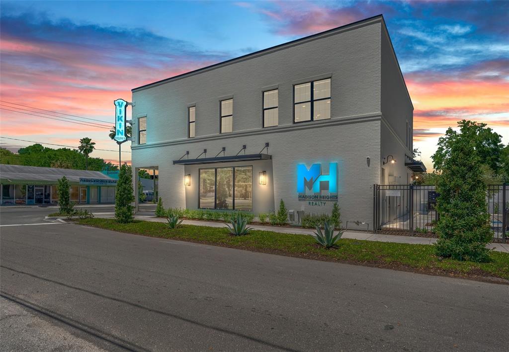 A two-story gray brick commercial building features a blue neon sign and landscaped front yard — 902 E CURTIS STREET UNIT 1, TAMPA, FL