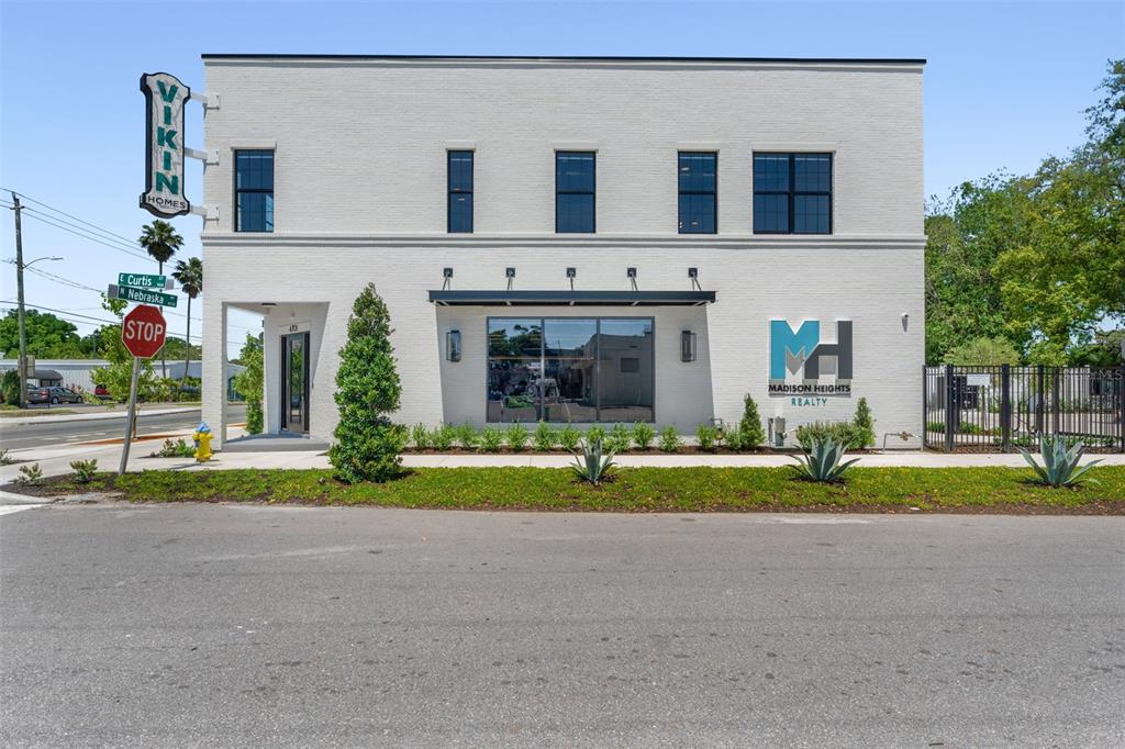 A two-story white brick commercial building with a corner sign and large front windows — 902 E CURTIS STREET UNIT 1, TAMPA, FL