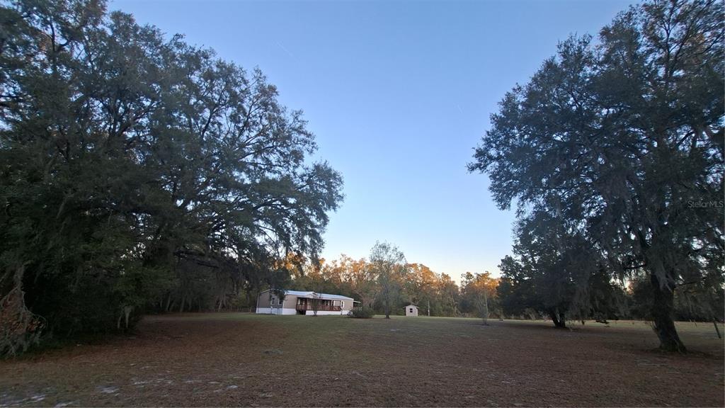 A single-story house sits on a large, grassy lot surrounded by mature oak trees — 3289 NE COUNTY ROAD 340, HIGH SPRINGS, FL