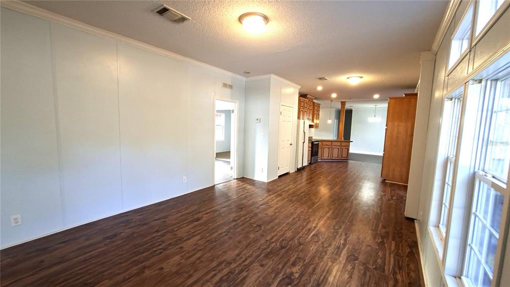 An open-concept living area features wood-look flooring, light blue walls, and a kitchen beyond — 3289 NE COUNTY ROAD 340, HIGH SPRINGS, FL