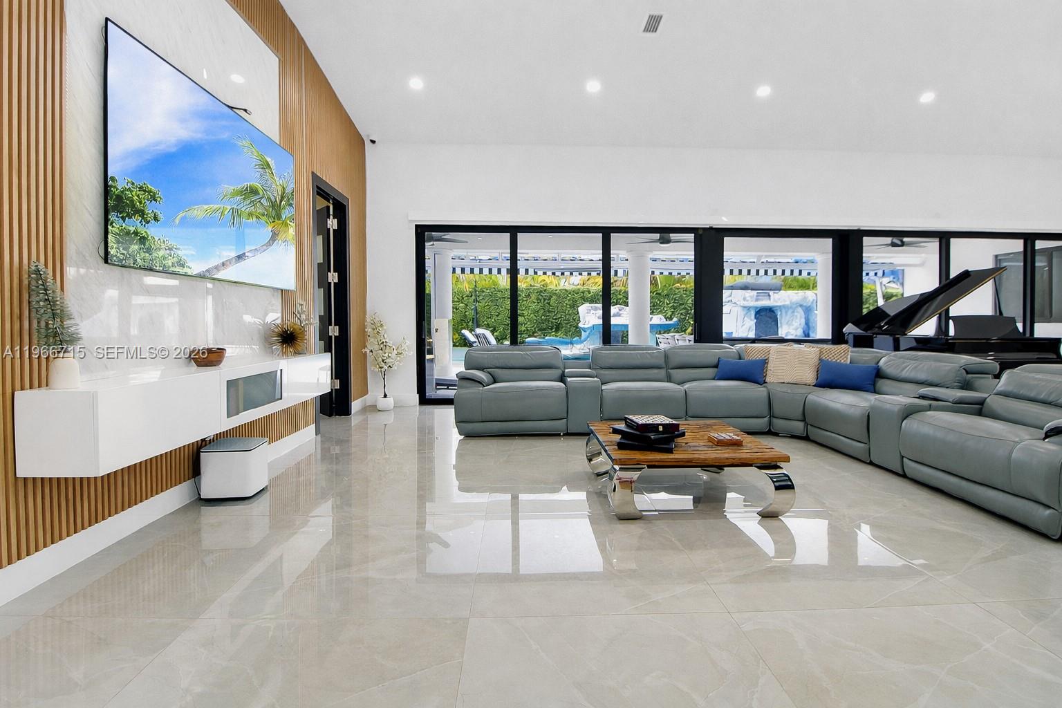 A modern living room features a large sectional sofa, wall-mounted television, and floor-to-ceiling windows — 2600 SW 128th Ave, Miami FL 33175, MIAMI, FL
