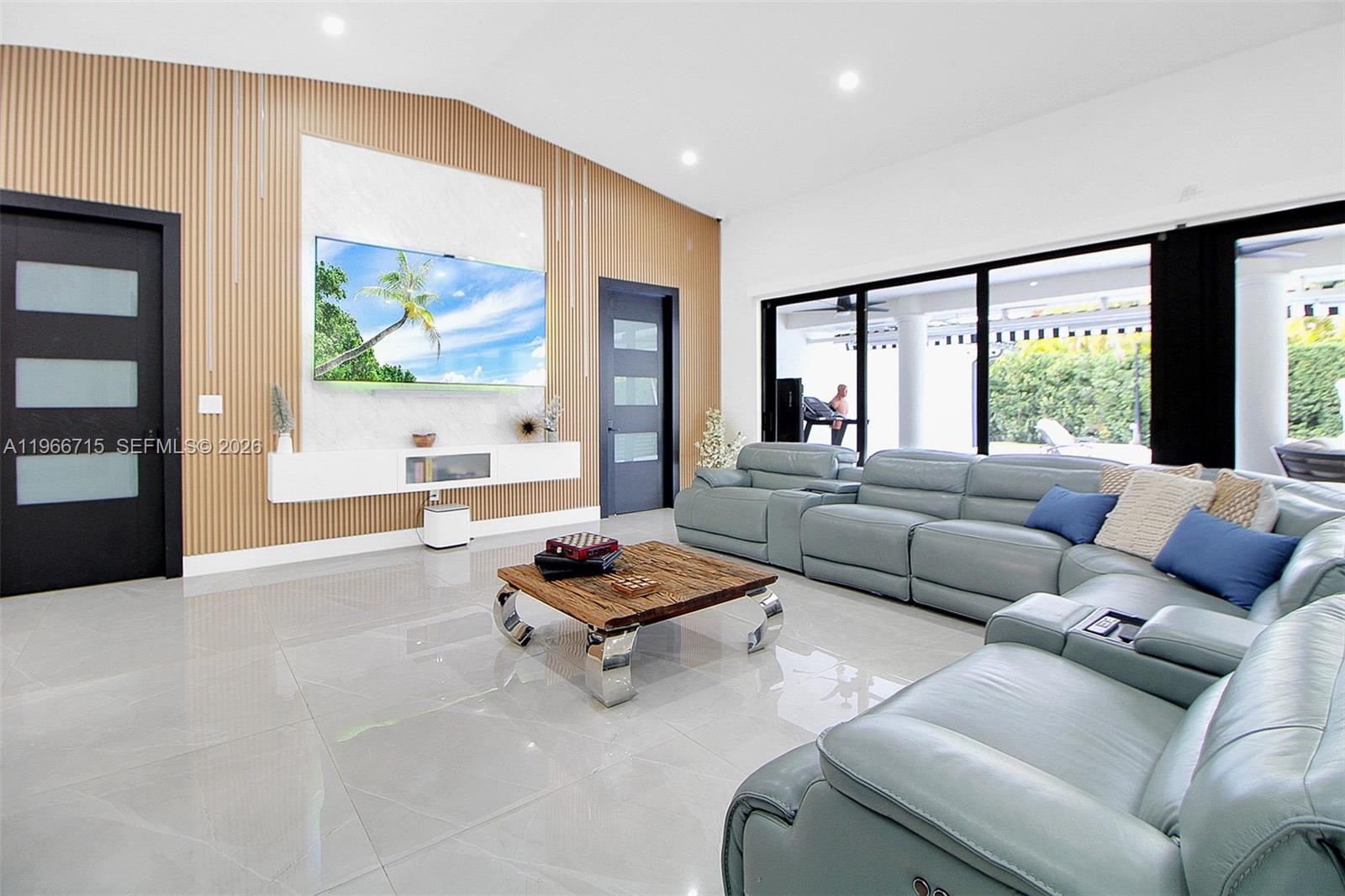 A modern living room features a wood-slat accent wall, a large sectional sofa, and floor-to-ceiling windows — 2600 SW 128th Ave, Miami FL 33175, MIAMI, FL