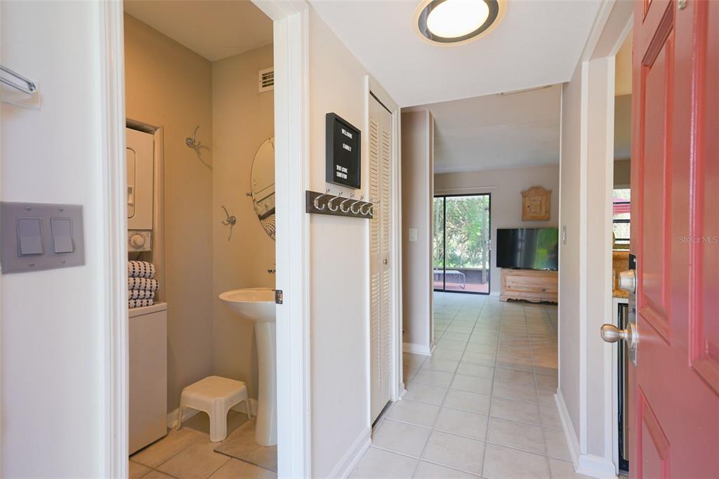 A view from an entryway looking into a tiled hallway, a laundry area, and living room — 2135 WATER MANIA COURT, KISSIMMEE, FL