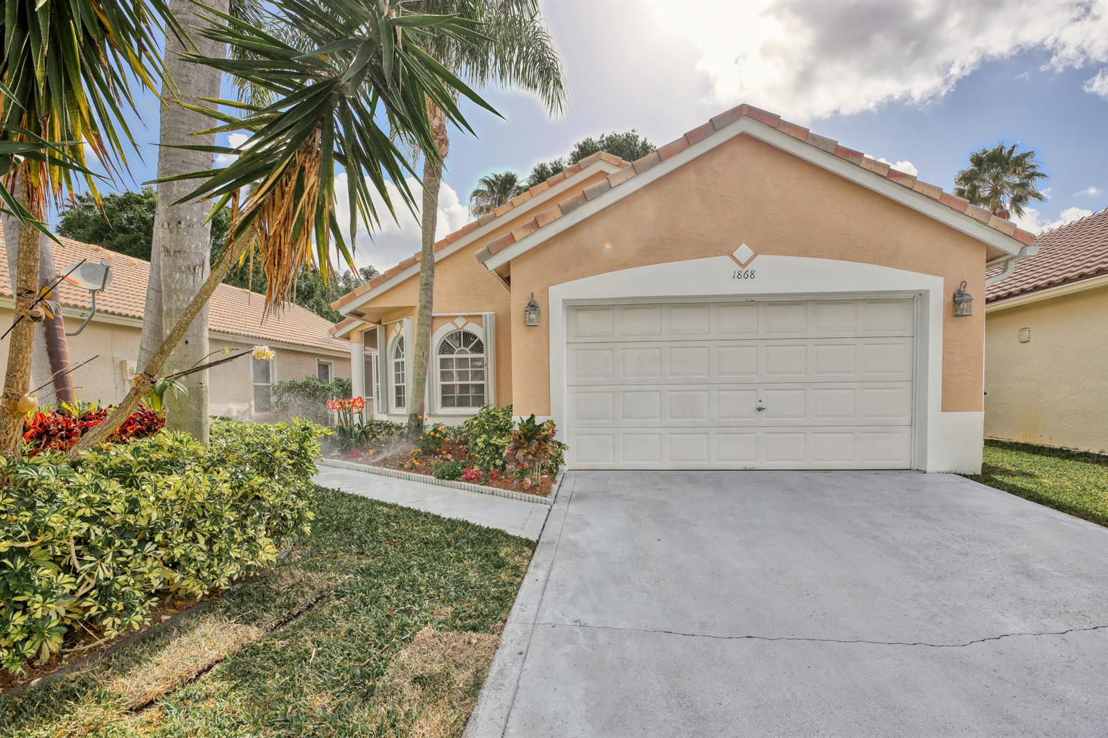 A single-story house with a beige stucco exterior, a two-car garage, and a concrete driveway — 1868 Barnstable Road, Wellington FL 33414, WELLINGTON, FL