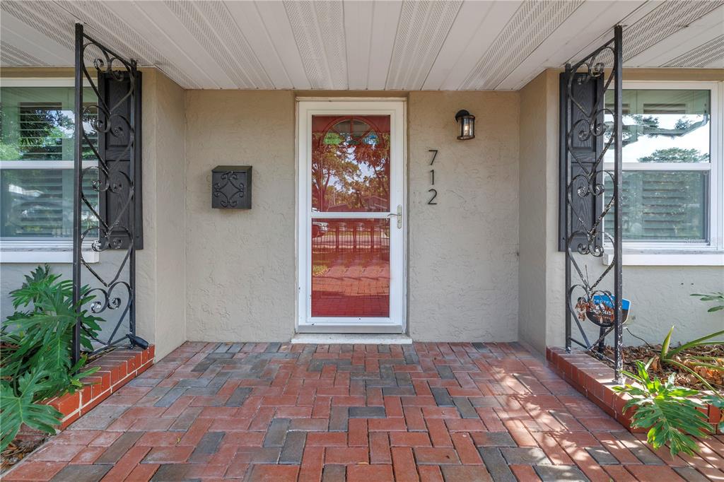A front porch with a brick floor, a glass storm door, and decorative metal columns — 712 43RD AVENUE N, ST PETERSBURG, FL