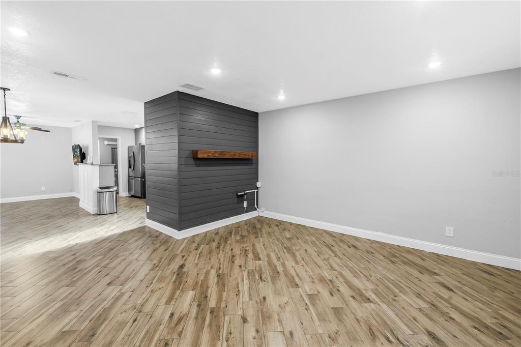 A living room features wood-look tile flooring, gray walls, and a dark shiplap accent wall — 712 43RD AVENUE N, ST PETERSBURG, FL