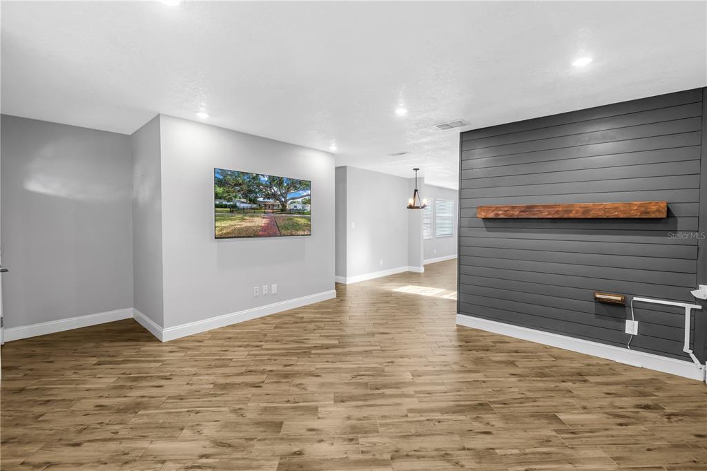 A living room features wood-look tile flooring, a gray shiplap accent wall, and a mounted television — 712 43RD AVENUE N, ST PETERSBURG, FL