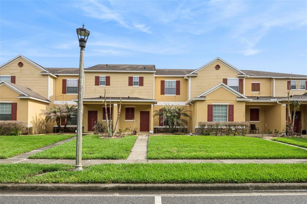 A two-story townhouse with yellow siding, red shutters, and a front walkway — 1732 BUCKEYE FALLS WAY, ORLANDO, FL