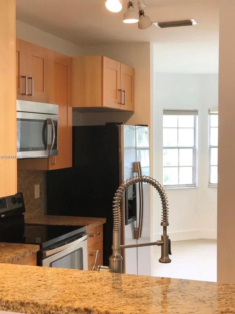 A kitchen features light wood cabinets, granite countertops, stainless steel appliances, and a gooseneck faucet — 16231 Emerald Cove Rd # 0, Weston FL 33331, WESTON, FL