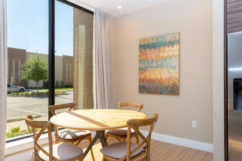 A dining area features a round wooden table, four chairs, and abstract wall art — 7505 BROOKLYN DRIVE, KISSIMMEE, FL