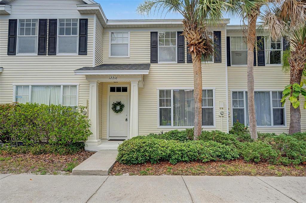 A two-story townhouse with light yellow siding, black shutters, and a front entrance — 12216 COUNTRY WHITE CIRCLE UNIT 12216, TAMPA, FL