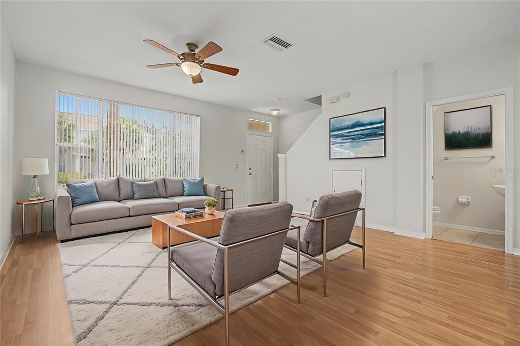 A living room features a gray sofa, two armchairs, a rug, and light wood flooring — 12216 COUNTRY WHITE CIRCLE UNIT 12216, TAMPA, FL