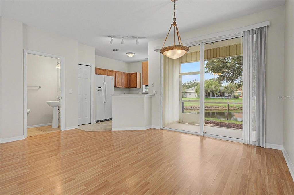 An open living area with wood-look flooring, a kitchen, and sliding doors to a patio — 12216 COUNTRY WHITE CIRCLE UNIT 12216, TAMPA, FL