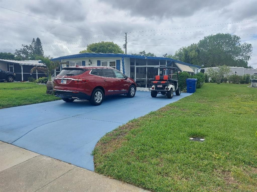 A red SUV and a golf cart are parked on a blue driveway before a house — 184 INDEPENDENCE AVENUE UNIT 8, PALM HARBOR, FL
