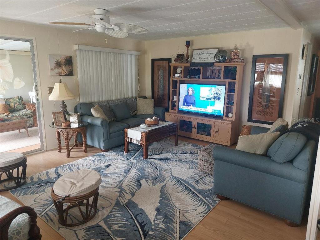 A living room features blue sofas, a patterned area rug, and a wooden entertainment center — 184 INDEPENDENCE AVENUE UNIT 8, PALM HARBOR, FL