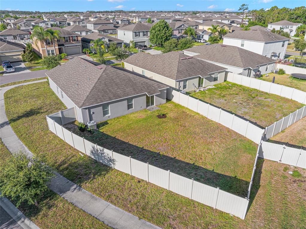 An aerial view shows a single-story house with a fenced backyard in a suburban neighborhood — 6810 TRENT CREEK DRIVE, SUN CITY CENTER, FL