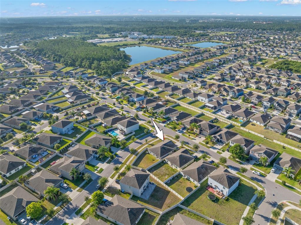 An aerial view shows a suburban neighborhood with single-family homes and a central lake — 6810 TRENT CREEK DRIVE, SUN CITY CENTER, FL
