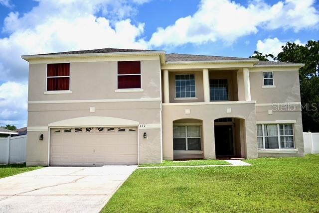 A two-story beige house features a two-car garage, a covered entryway, and a grassy lawn — 632 BITTERN COURT, KISSIMMEE, FL