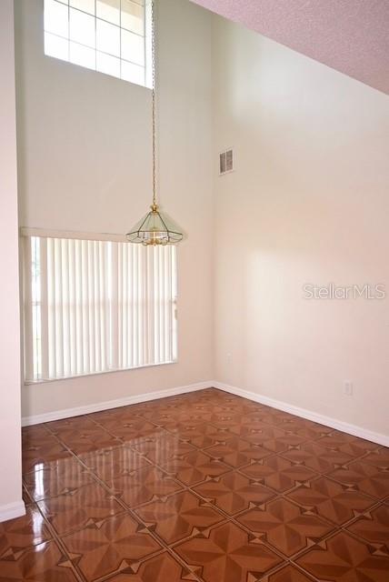 A dining room with high ceilings, a hanging pendant light, vertical blinds, and tiled flooring — 632 BITTERN COURT, KISSIMMEE, FL