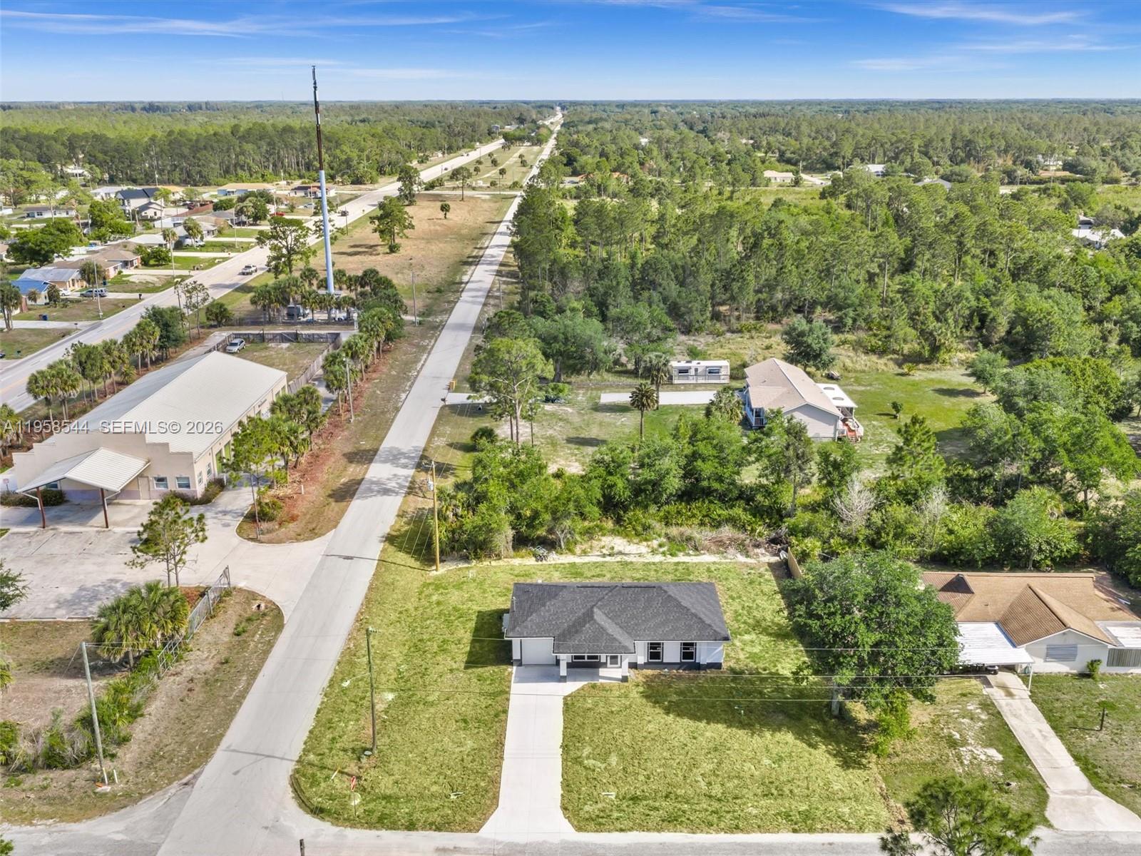 An aerial view shows a single-story house with a dark roof and a concrete driveway — 2401 E 11th St, Lehigh Acres FL 33936, LEHIGH ACRES, FL