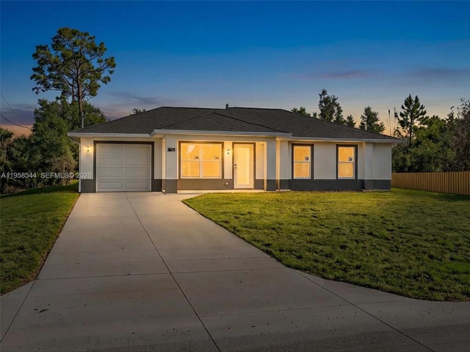 A single-story house with a white and gray exterior, a garage, and a concrete driveway — 2401 E 11th St, Lehigh Acres FL 33936, LEHIGH ACRES, FL