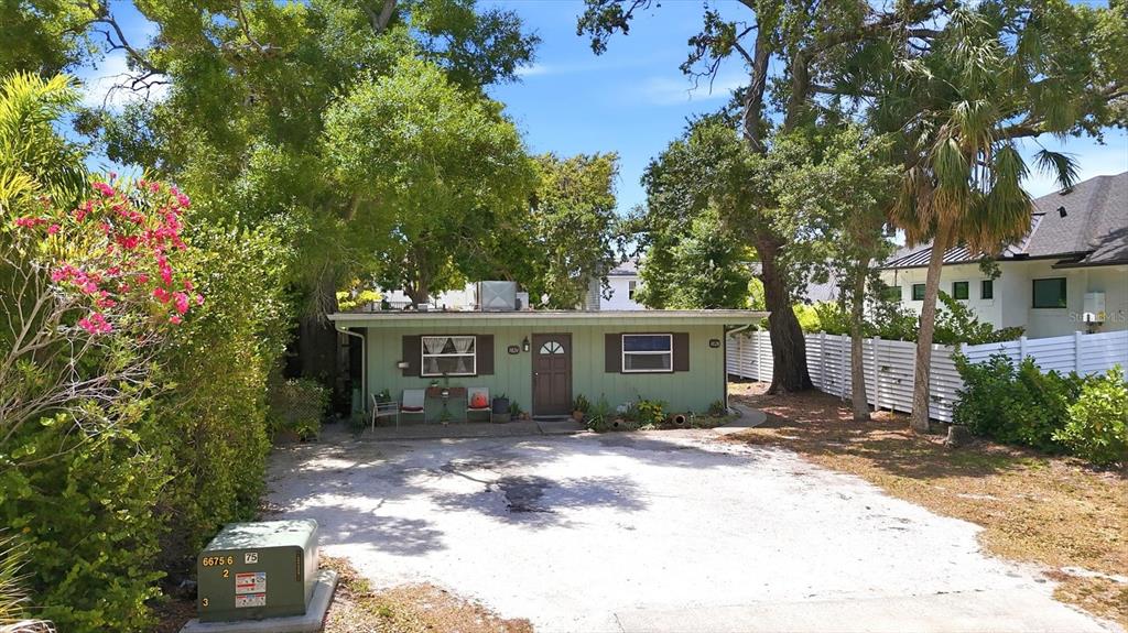 A single-story green house with a front porch sits behind a large gravel driveway — 1824 WEBBER STREET, SARASOTA, FL
