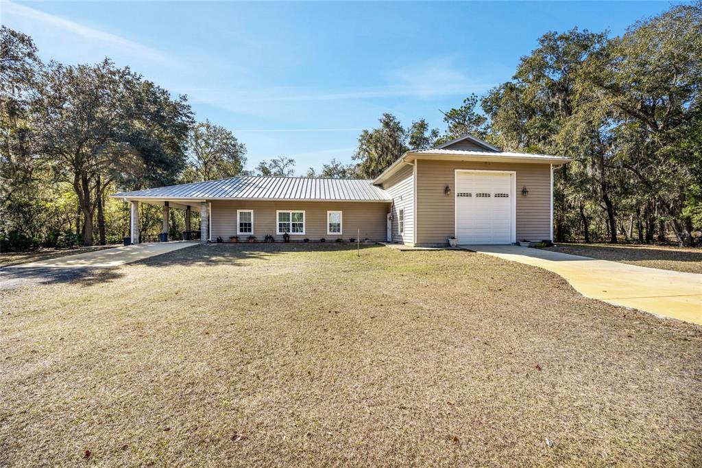 A single-story house with a metal roof, attached garage, and a covered porch — 16602 NE 124TH AVENUE, WALDO, FL
