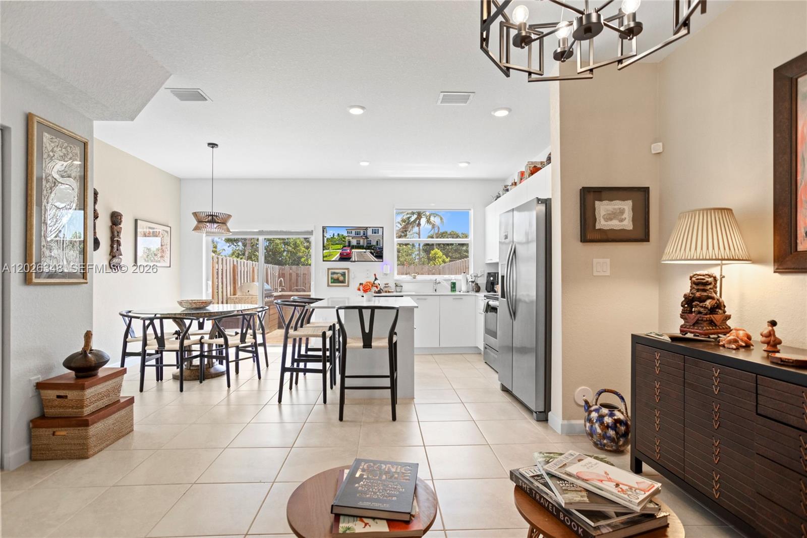 An open-concept kitchen and dining area features tile flooring, white cabinetry, and a sliding door — 12317 NW 23rd Ct, Miami FL 33167, MIAMI, FL