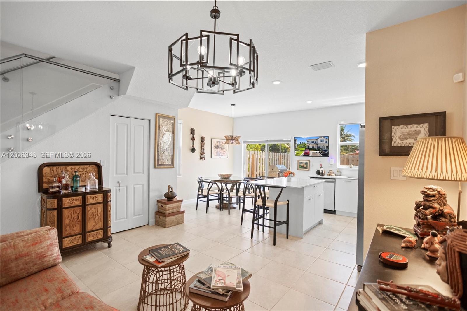 An open-concept living and dining area features a large chandelier, kitchen island, and tiled floors — 12317 NW 23rd Ct, Miami FL 33167, MIAMI, FL