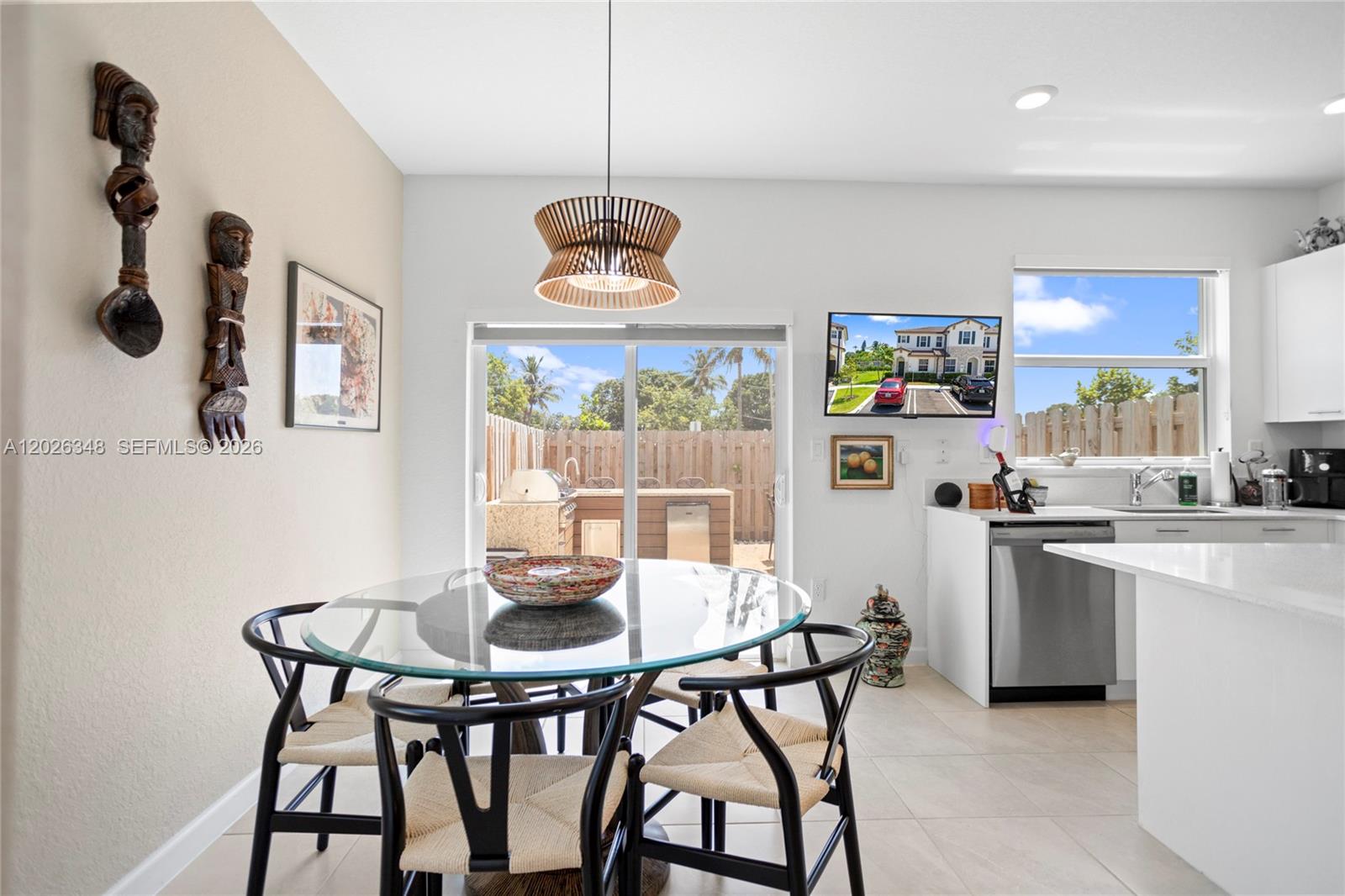 A dining area with a glass table, wooden chairs, and a sliding door to a patio — 12317 NW 23rd Ct, Miami FL 33167, MIAMI, FL