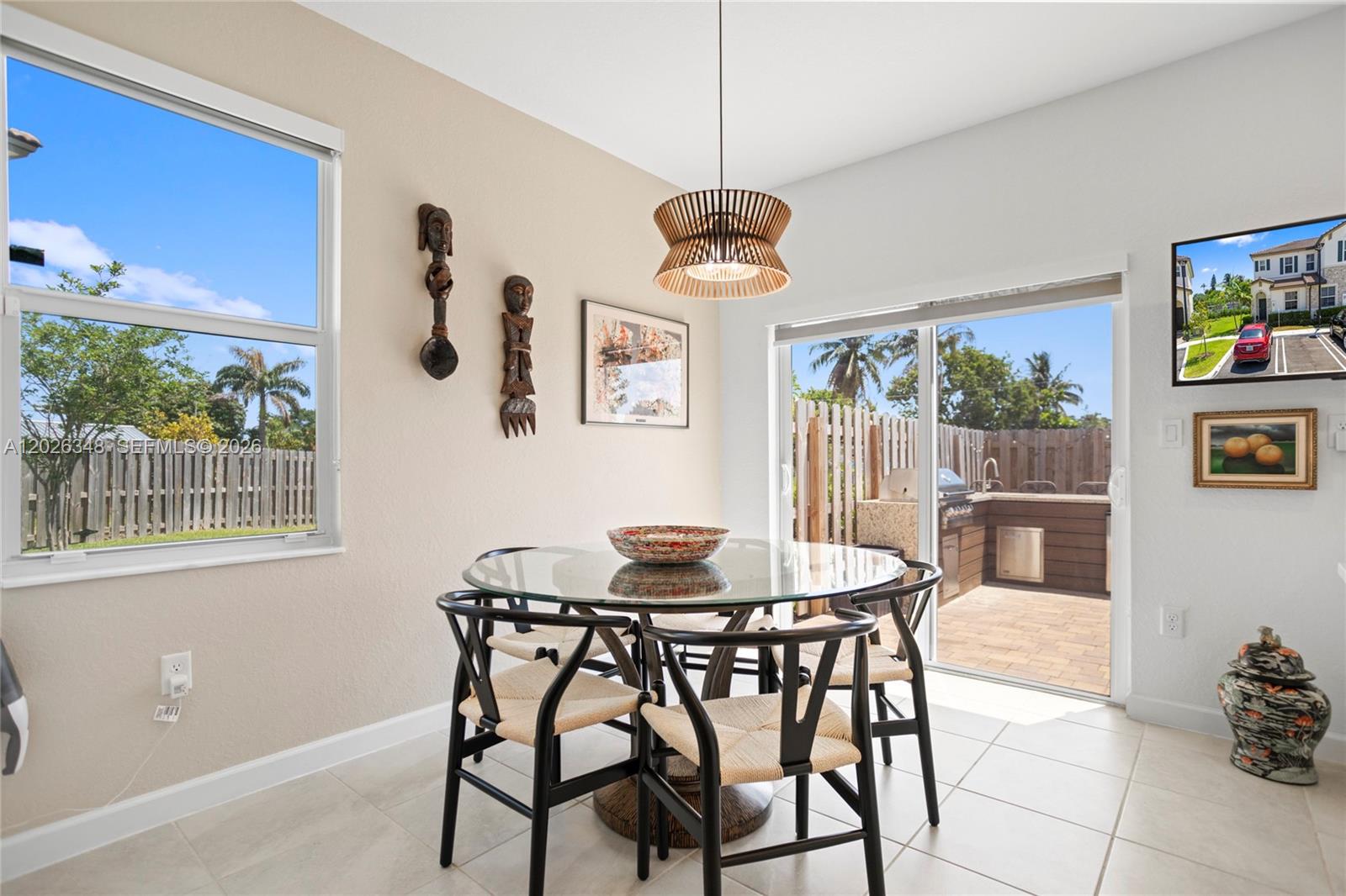 A dining area with a glass table, black chairs, and a sliding door to a patio — 12317 NW 23rd Ct, Miami FL 33167, MIAMI, FL